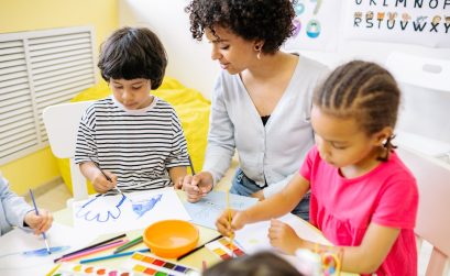 two young students painting with their school teacher